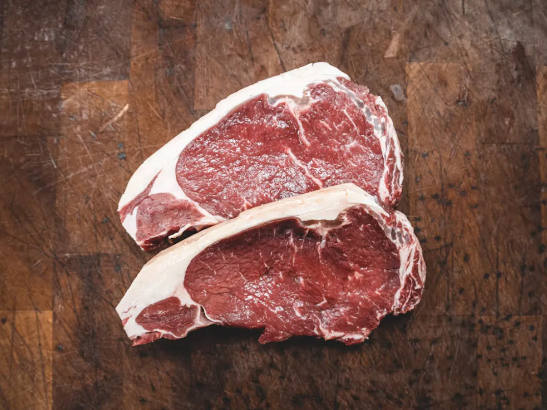 Bistecche di carne fresca su tagliere di legno